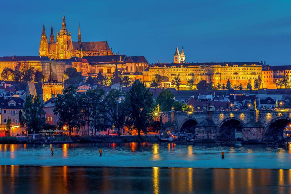 Prager Burg mit Veitsdom und Karlsbrücke am Abend, beleuchtet, an der Moldau